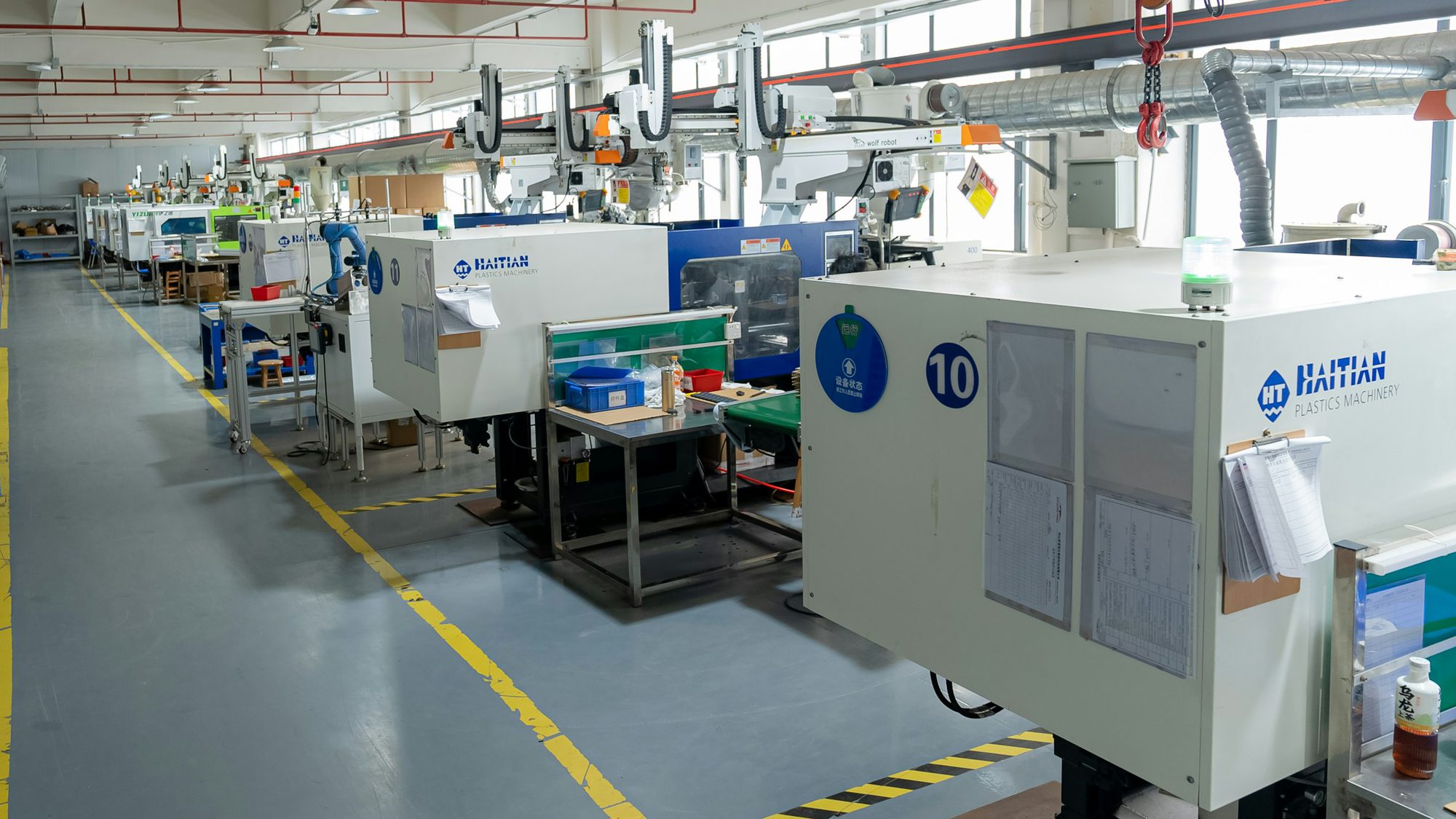 Row of injection moulding machines running recycled plastic on a factory floor